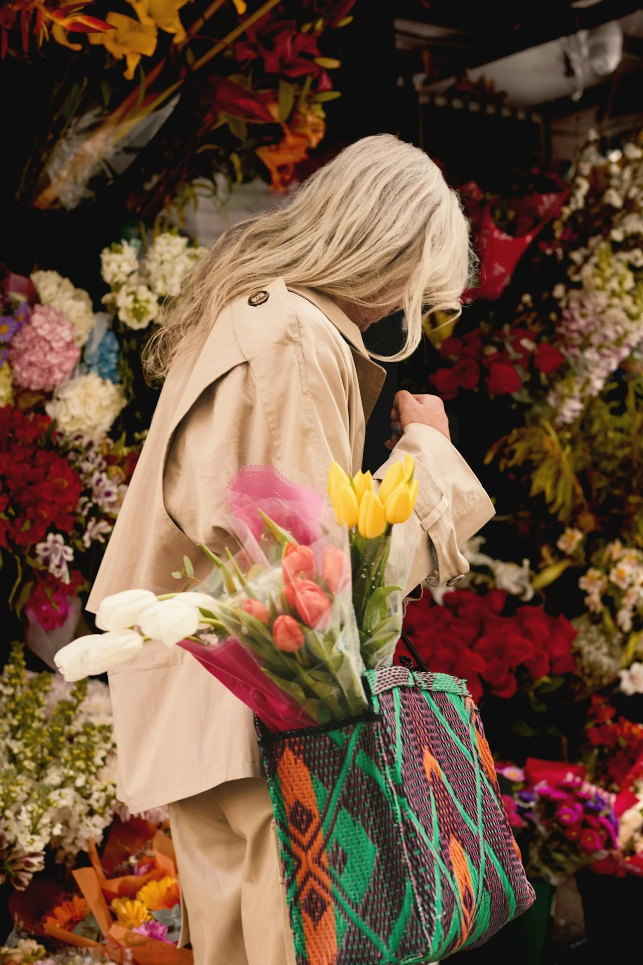 Woman with silver hair at a flower market carrying colourful tulips