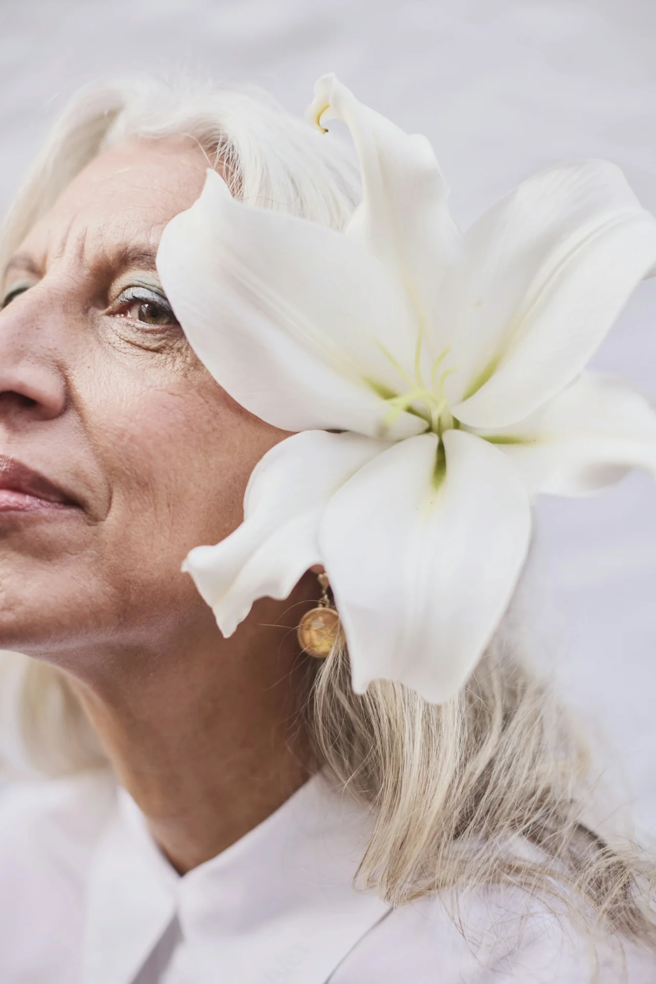 Close portrait of a woman with silver hair and a white lily